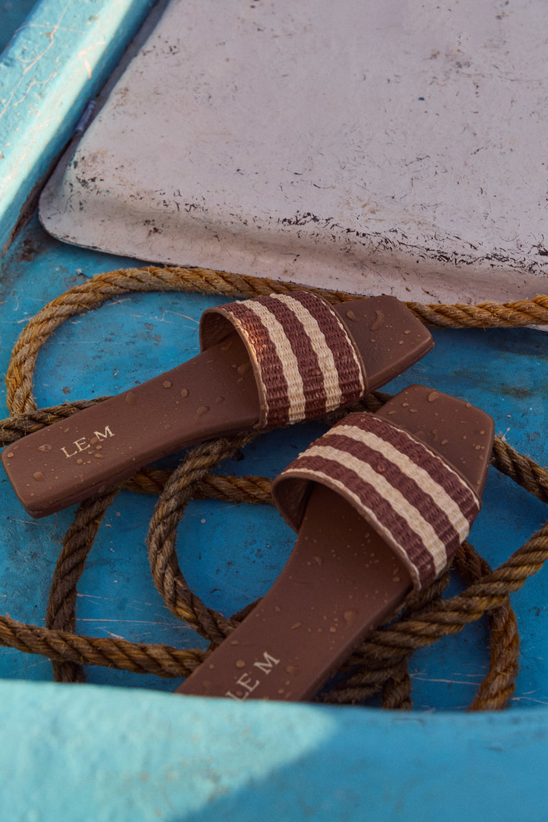 Honey Piper Sandals with woven striped straps, resting on coiled rope, embody classic, effortless style. Perfect for fun adventures, offering high-end comfort and craftsmanship.