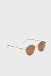 Sunski round metal frame sunglasses with thin gold rims and brown tinted lenses are displayed on a plain white background.