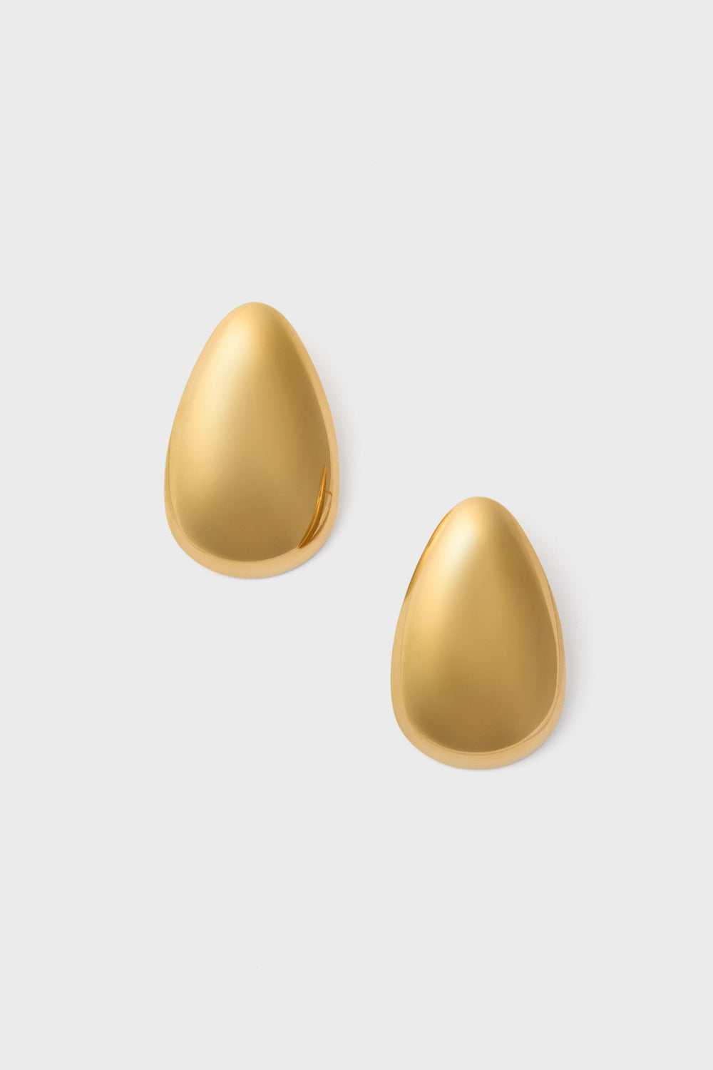 A pair of smooth, gold, teardrop-shaped Petit Moments Essie Earrings crafted in stainless steel are elegantly displayed.