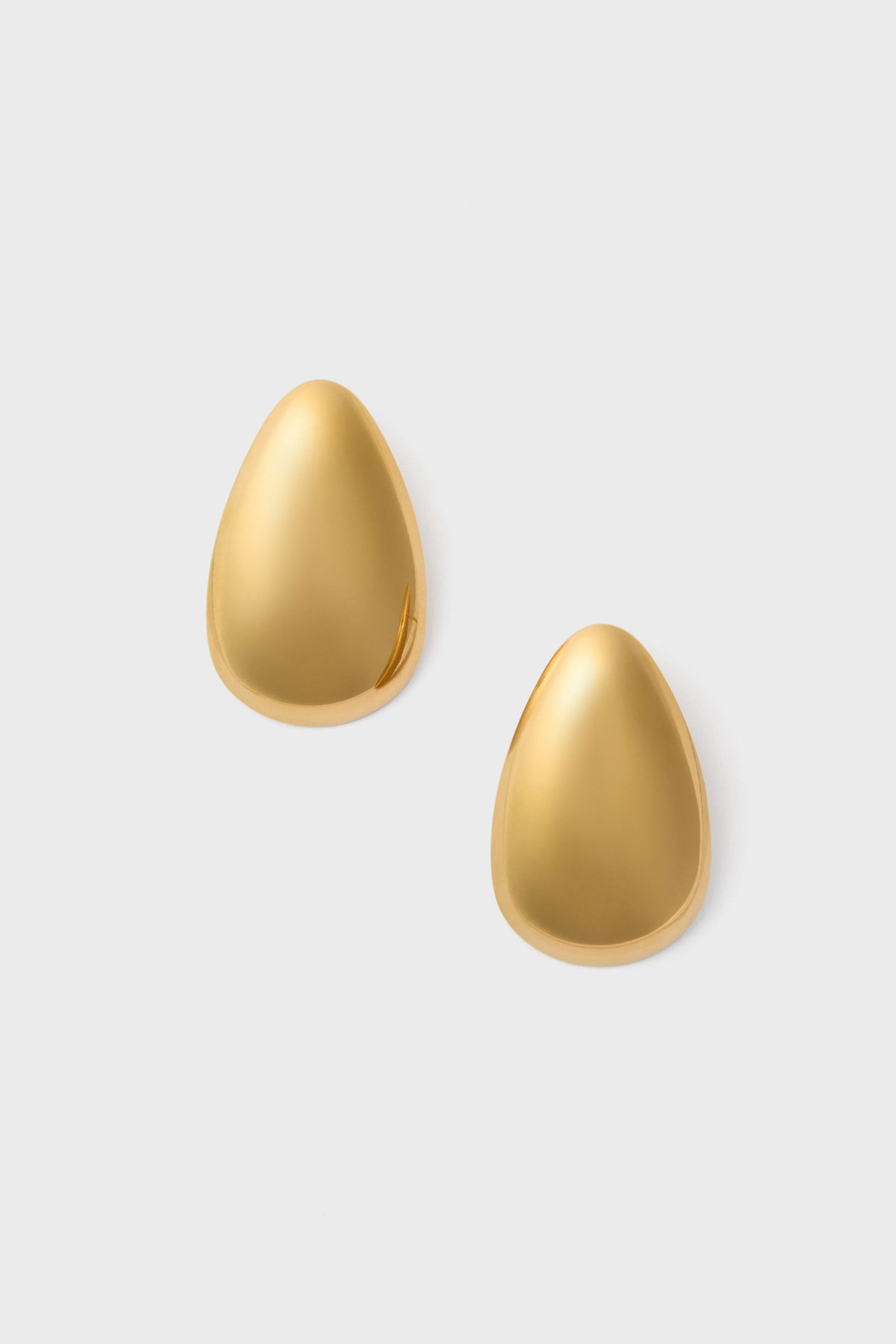 A pair of smooth, gold, teardrop-shaped Petit Moments Essie Earrings crafted in stainless steel are elegantly displayed.