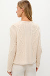 Woman wearing the Cream Cable Knit Pearl Collins Cardigan, showcasing its classic, high-end cable-knit pattern with faux pearls, embodying effortless style and fun sophistication.