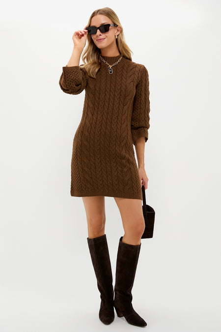 Model in classic Coffee Cable Knit Lucia Mini Dress, effortlessly styled with knee-high boots, sunglasses, and a gold necklace, embodying a chic, high-end, and fun fall look.