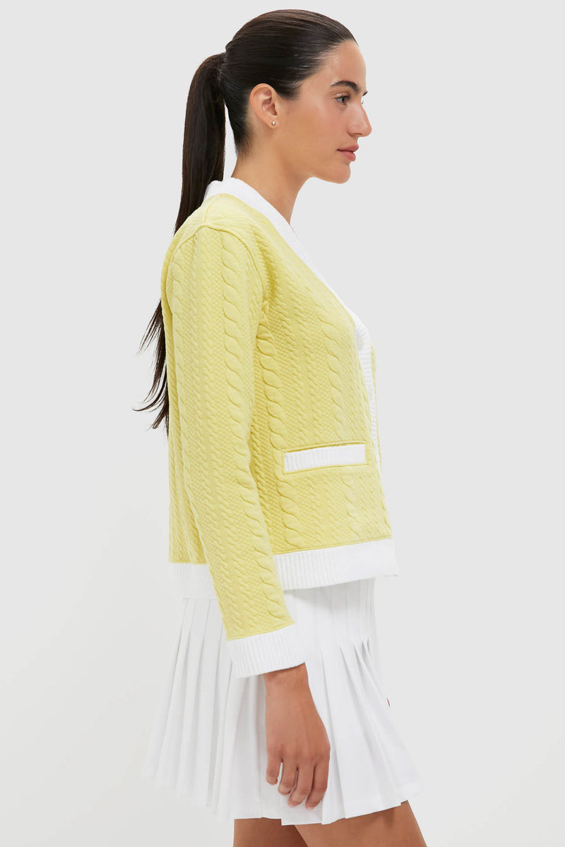 Woman wearing the Lemongrass Cable Charley Cardigan, a classic yet effortless pastel-yellow piece with contrast trim, front button placket, and slit pockets, exuding high-end sporty charm.