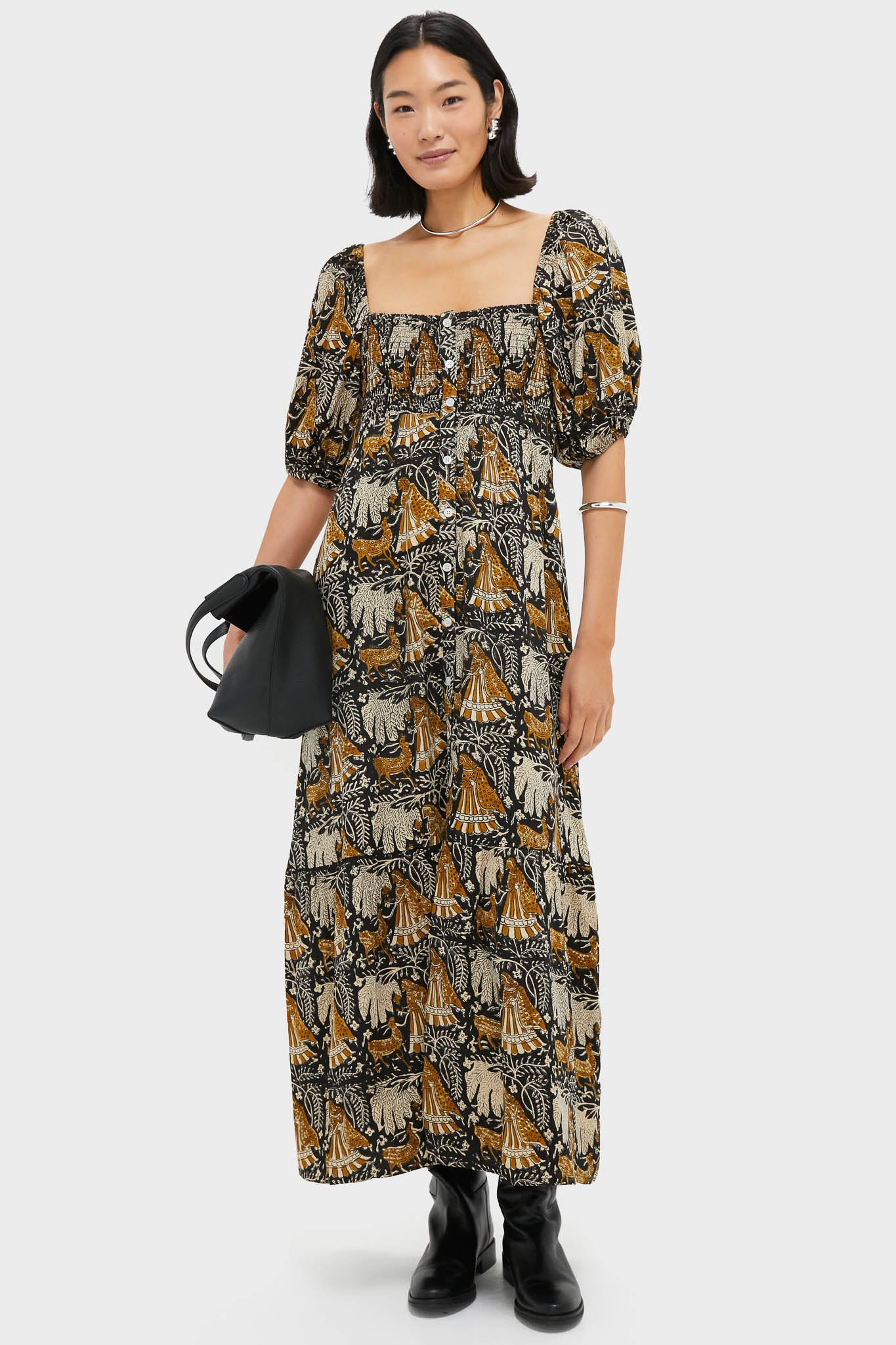 Model wearing the Story Print Santiago 3 Maxi Dress with puff sleeves and a smocked bodice, styled with black boots and a handbag for a classic, effortless look.