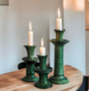 Three green ceramic candle holders of different heights from Tuckernuck Vintage Accessories, each with a lit white candle, displayed on a wooden surface.