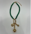 A Tuckernuck Vintage Accessories beaded green necklace with a gold chain extension, featuring three gold pendants—a sun, ball, and clear crystal on a metal ring.