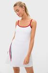 A woman wears a Tnuck Sport white sleeveless tank dress with red trim, a vertical red and navy stripe near the hem, and a flattering compression fit.
