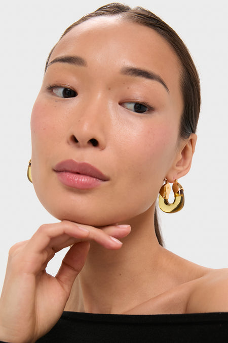 Young woman wearing Apple Organic Hoops, chunky polished gold earrings, exuding classic, effortless elegance. Perfect for fun, high-end styling with various outfits.