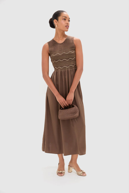 Model wearing the Regio Brown Silk Gioia Midi Dress with a smocked bodice and flowy skirt, styled effortlessly with a woven clutch and block-heel sandals.