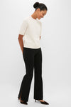 Woman in black trousers and heels wearing the Ivory Jackson Sweater, an effortlessly classic, oversized cashmere top with short sleeves and a crew neck, exuding high-end style.
