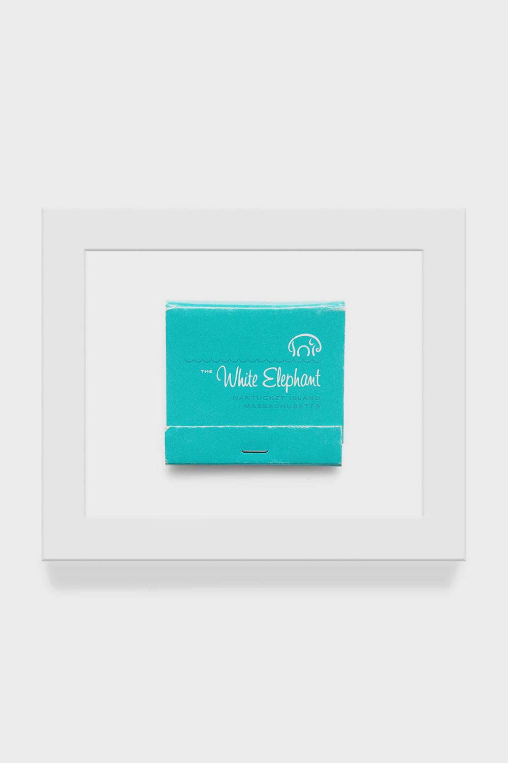 A framed macro photo from Matchbook Diaries by Charles Ryan Clarke features a turquoise White Elephant Nantucket matchbook print, elegantly centered with a white elephant logo.