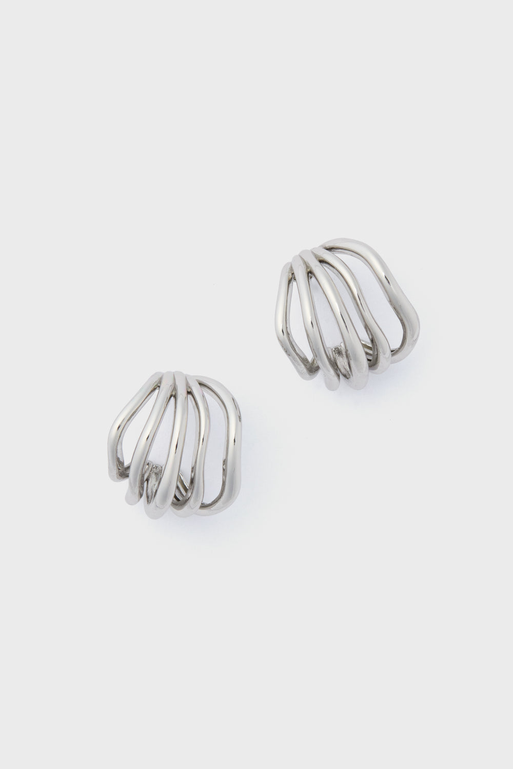 The Petit Moments Silver Sonoma Earrings showcase a sleek silver metal with an open, curved, and layered design—an elevated take on classic hoops.