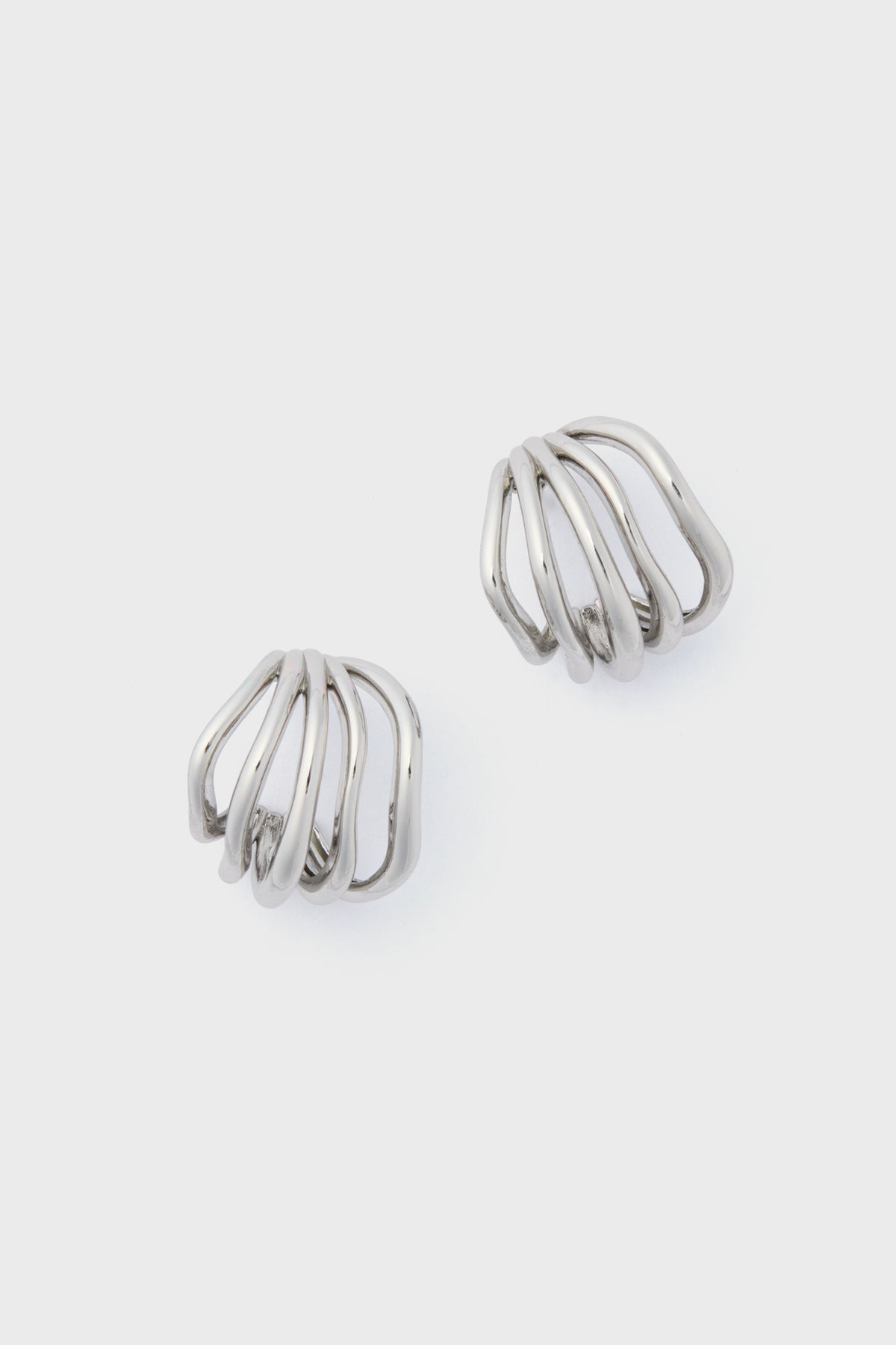The Petit Moments Silver Sonoma Earrings showcase a sleek silver metal with an open, curved, and layered design—an elevated take on classic hoops.