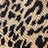 A close-up of beige fabric featuring a bold black leopard print pattern.