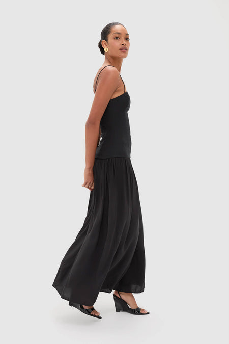 Woman wearing the Black Lenise Maxi Dress with a fitted bodice, drop waist, and flowing A-line skirt, embodying a classic, effortless, high-end style.