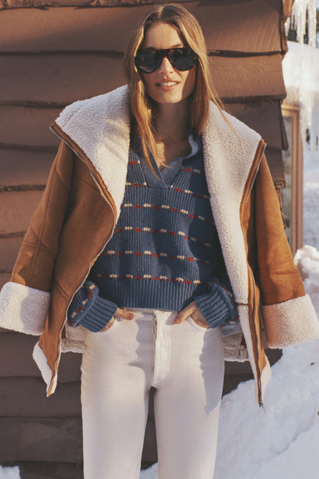 Person in snowy setting wearing the Camel Fur Trim Suede Coat, a classic, effortless layer with plush trim, perfect for a fun, high-end winter look.