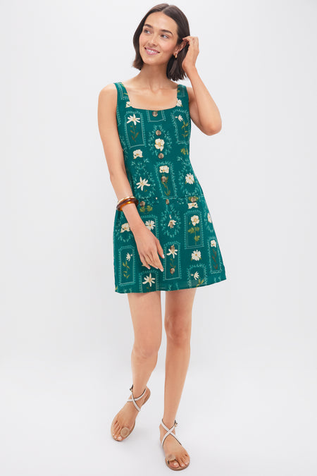 Woman in a classic, sleeveless Teal Stem Merrit Mini Dress with botanical motifs, exuding effortless elegance; perfect for fun, high-end gatherings.