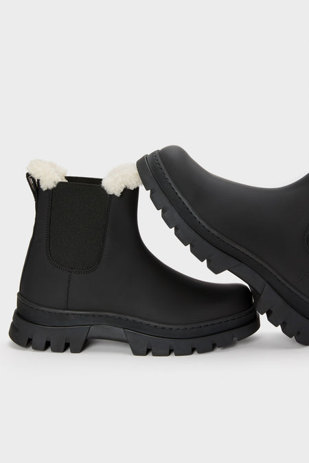 Jenni Kayne black ankle boots with chunky soles and white faux fur lining at the top, displayed against a plain light background.