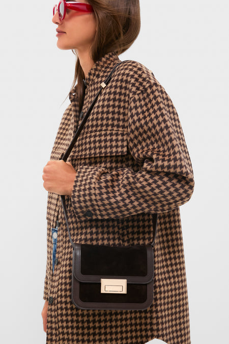 Model in profile wears a classic houndstooth coat and red sunglasses, showcasing the high-end, effortless Tmoro Suede Desi Crossbody Bag with gold-tone clasp.