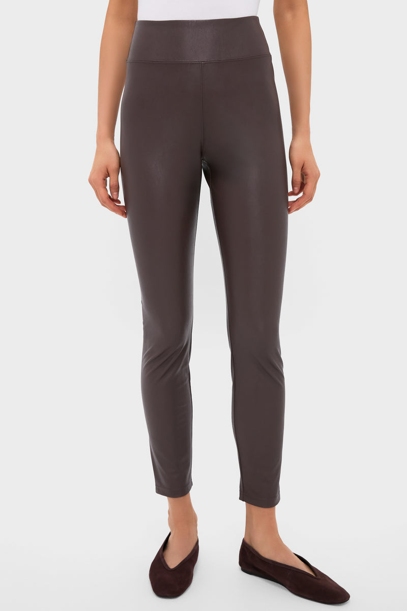 A person confidently wears Tuckernuck high-waisted, fitted dark brown faux leather leggings with matching flat shoes.
