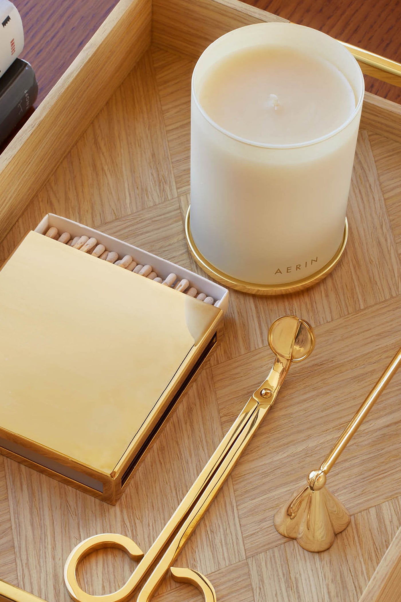 Lou Wick Trimmer on a classic wooden tray with a frosted AERIN candle, gold matchbox, and candle tools, offering effortless, high-end candle care.