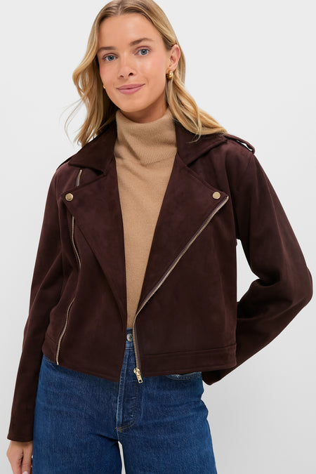 A woman faces the camera in a Hyacinth House dark brown faux suede boxy jacket, layered over a beige turtleneck and blue jeans—an essential autumn look.