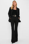 Woman in sleek, all-black ensemble featuring Black Sophie II Pants with flared legs and mid-rise waist, styled effortlessly with a blazer and gold accessories for a classic, high-end look.