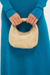 Woman in a teal dress holds the Gold Eden Woven Hobo, a classic, high-end handbag with circular handles, perfect for an effortless, fun style.