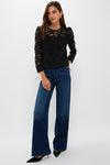Model in Black Lace Elodie Blouse with floral cutouts, paired effortlessly with high-waisted jeans and kitten heels, showcasing a classic yet fun high-end style.