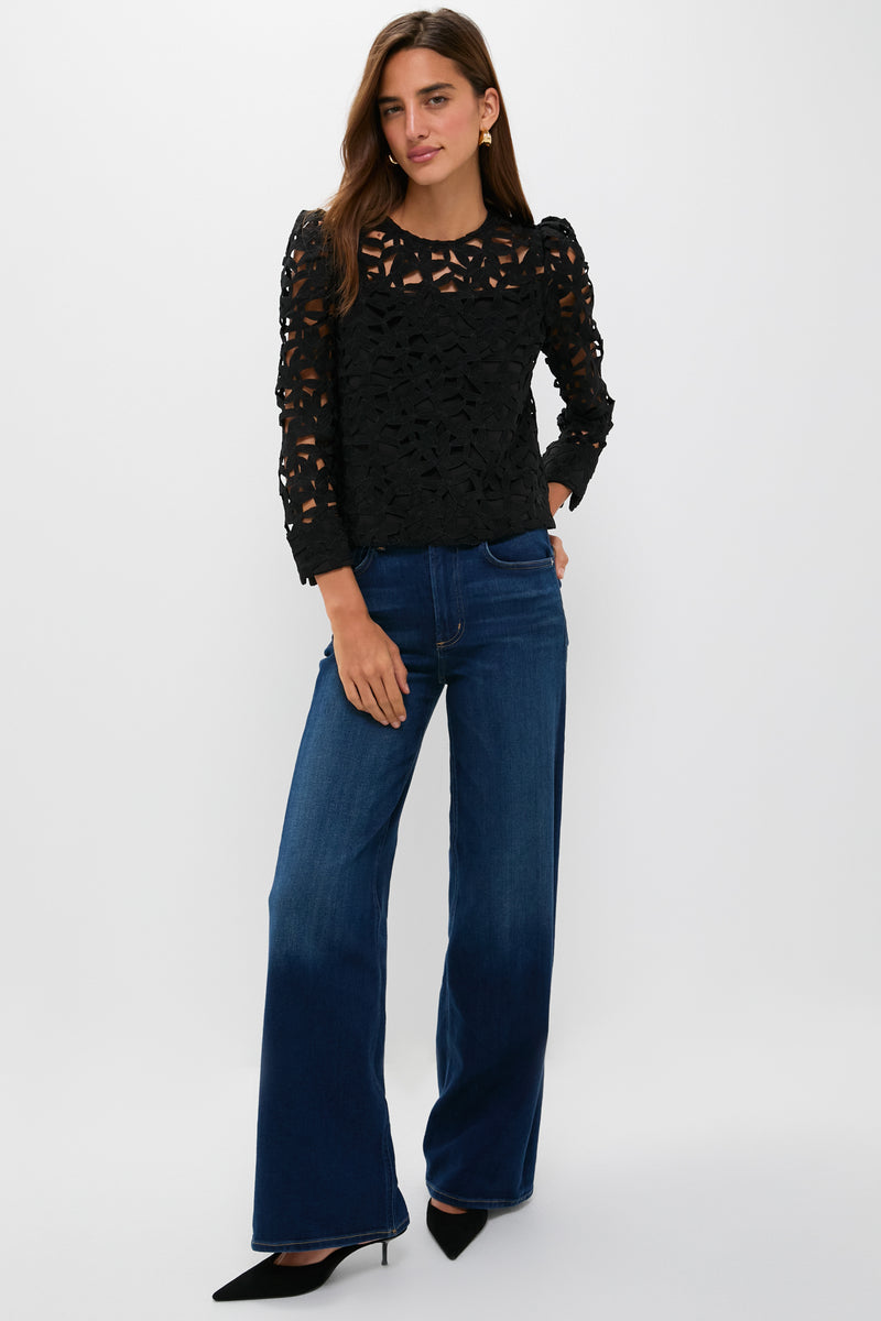 Model in Black Lace Elodie Blouse with floral cutouts, paired effortlessly with high-waisted jeans and kitten heels, showcasing a classic yet fun high-end style.