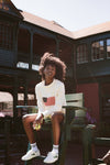 Woman sitting on a green chair in a white sweater with the American flag. 