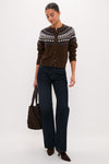 Woman modeling the classic Chestnut Amina Fairisle Sweater, featuring an effortless multicolored yoke pattern, paired with high-end dark-wash jeans and stylish brown suede ankle boots.
