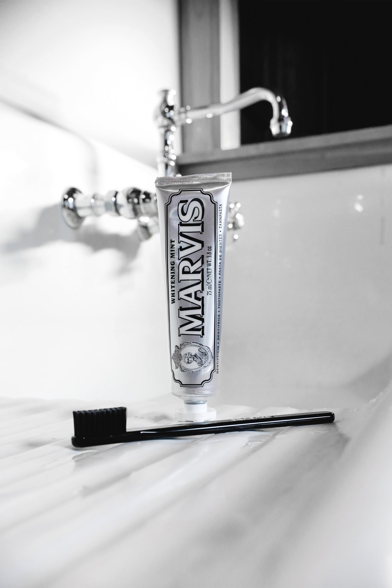 Marvis Whitening Mint toothpaste stands elegantly by a classic sink, paired with a sleek toothbrush, offering an effortless, high-end dental care experience.