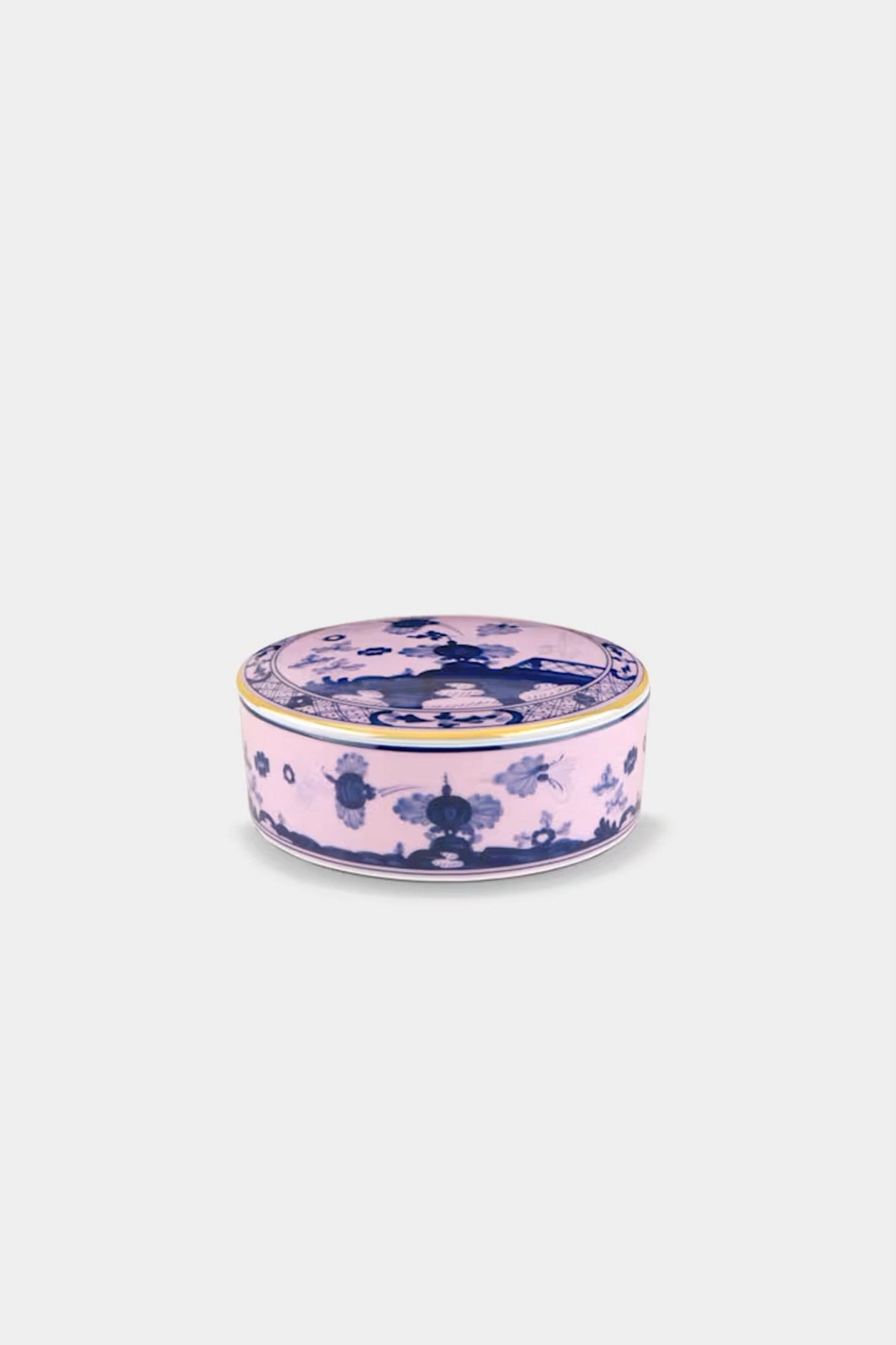 A round Ginori 1735 porcelain trinket box with a pink background, blue floral patterns, and a gold rim, displayed on a plain white surface.