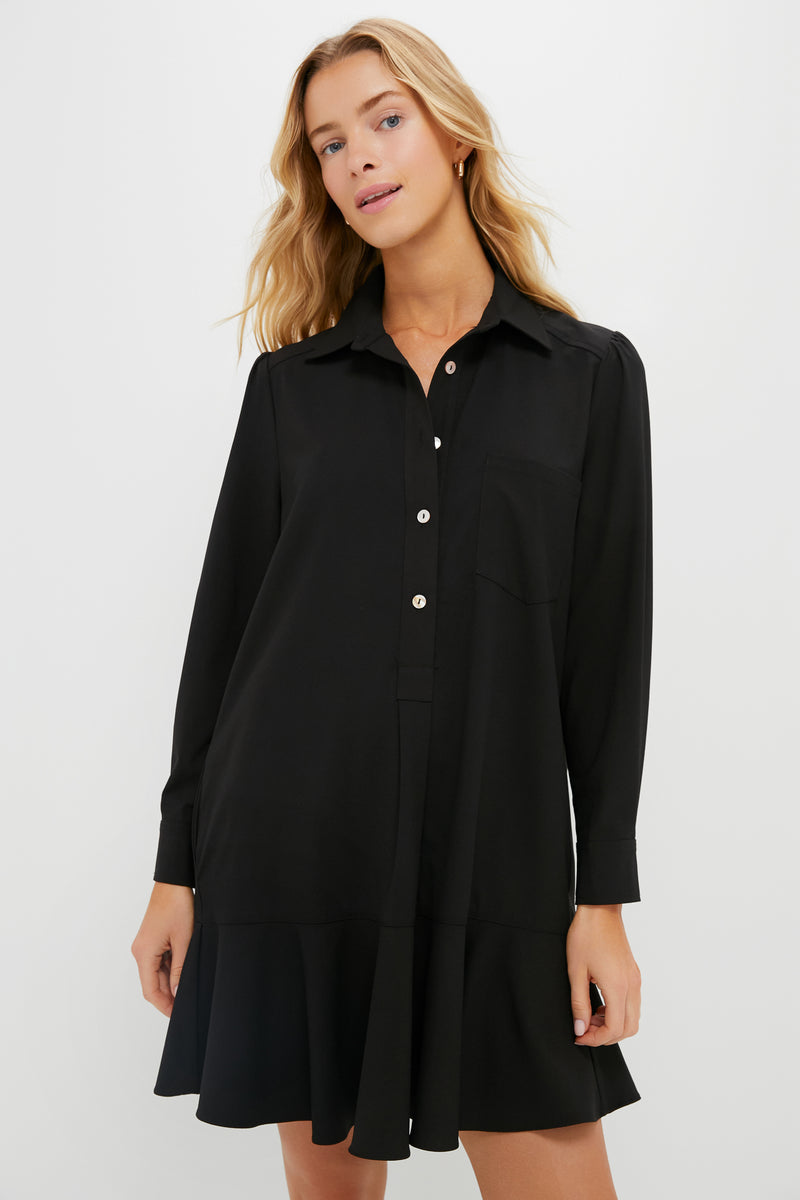 A woman wearing a long-sleeve, button-down black Tuckernuck dress with a collar and ruffled hem.
