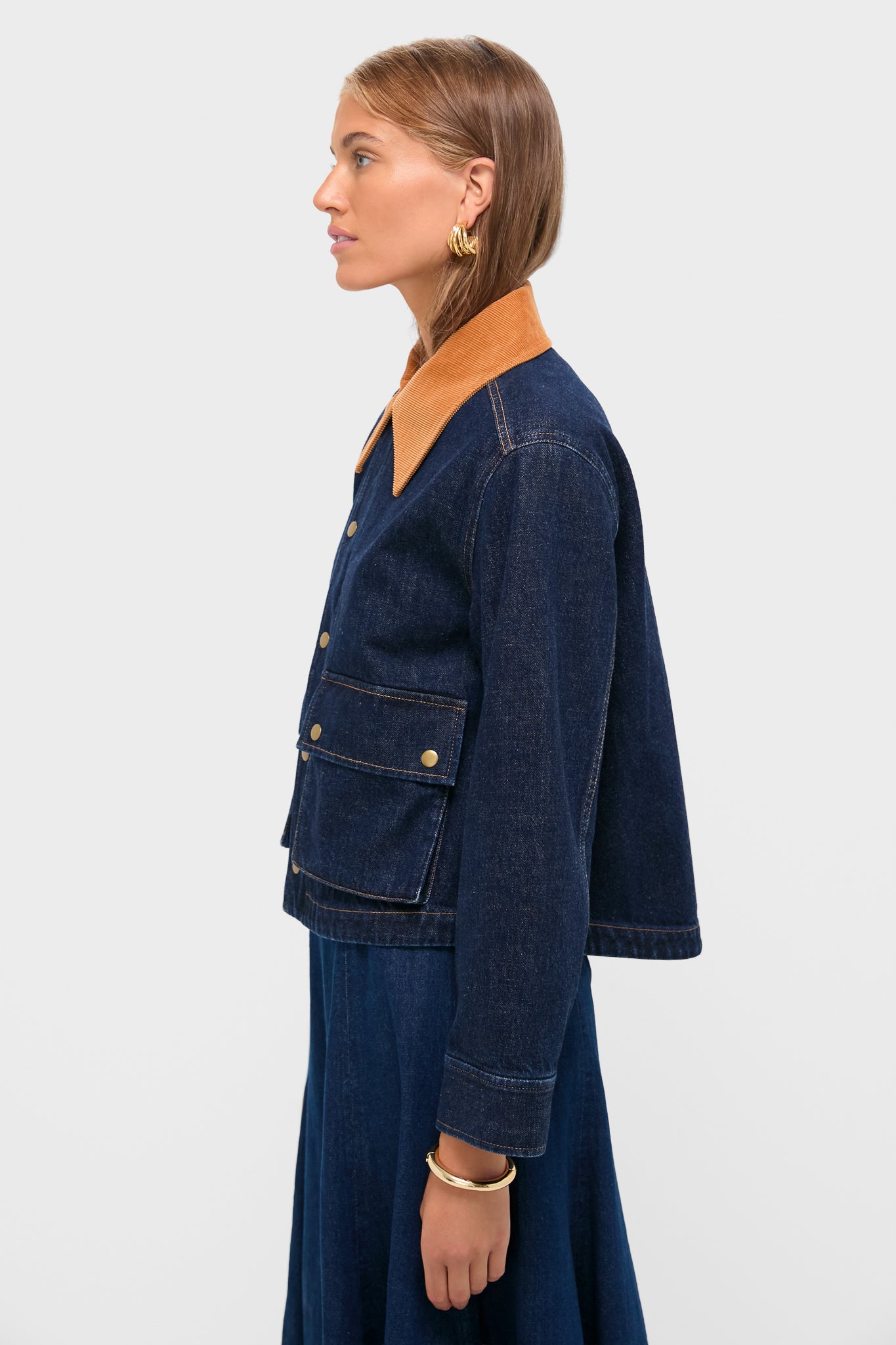 Young woman models the Midnight Rinse Denim Swingy Jacket, featuring a classic boxy-cut with tan corduroy collar and brass snap pockets, exuding an effortless, high-end style.