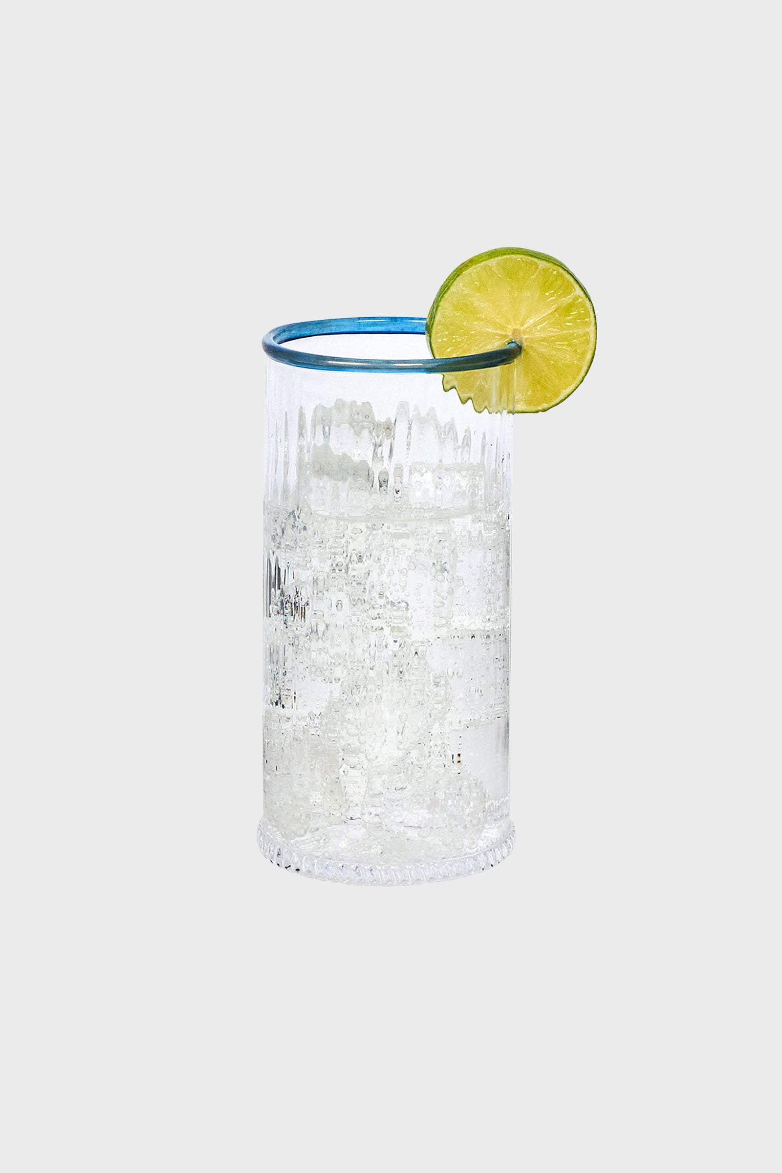 Chambray Nell Highball: A classic, high-end glass with ribbed texture, filled with fizzy liquid and lime garnish, embodies effortless fun for stylish cocktail moments.