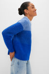 Woman in profile wearing the classic Blue Cocha Sweater, a cozy, high-end knit with mock neck and ribbed finishes, embodying effortless style and fun elegance.