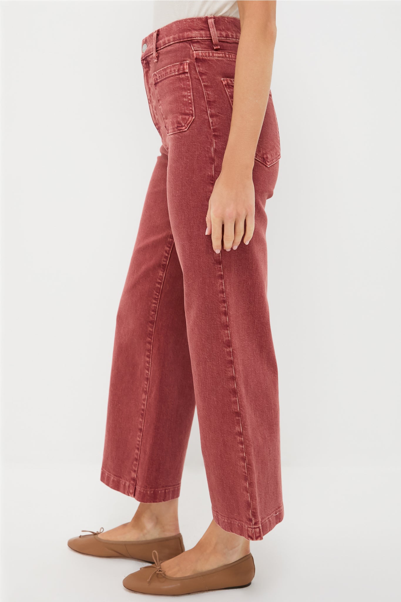 Someone stands sideways against a plain white background, wearing LE JEAN spice-colored high-rise wide-leg jeans paired with brown ballet flats.
