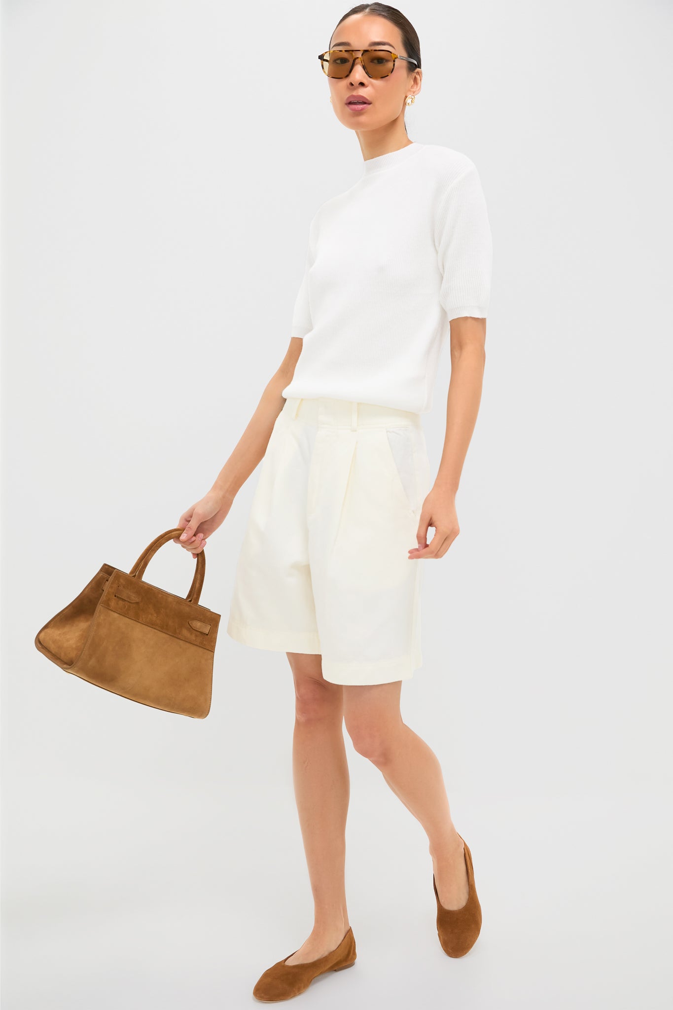 Model showcasing an effortless, high-end summer look with Gold Silver Hailey Studs, adding a classic, fun touch to her minimalist ensemble of white knit top and bermuda shorts.