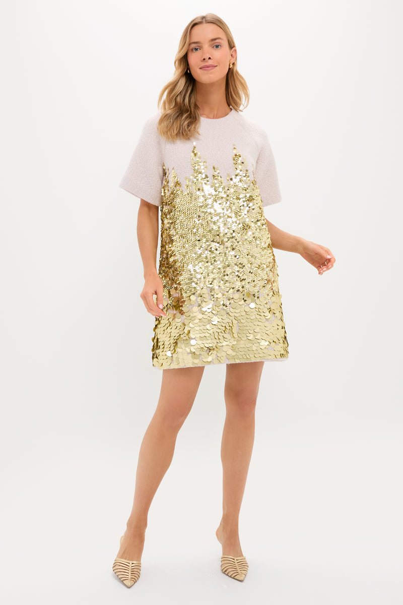 A woman wears the Hunter Bell Aerin Dress, a short-sleeved, light-colored evening shift with gold sequins on the lower half, paired with pointed-toe shoes, standing against a plain white background.