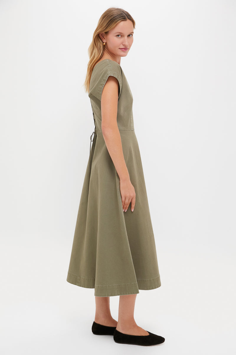 Woman in profile wearing the classic Burnt Olive Chino Solen Midi Dress with cap sleeves and lace-up back, styled effortlessly with black ballet flats.