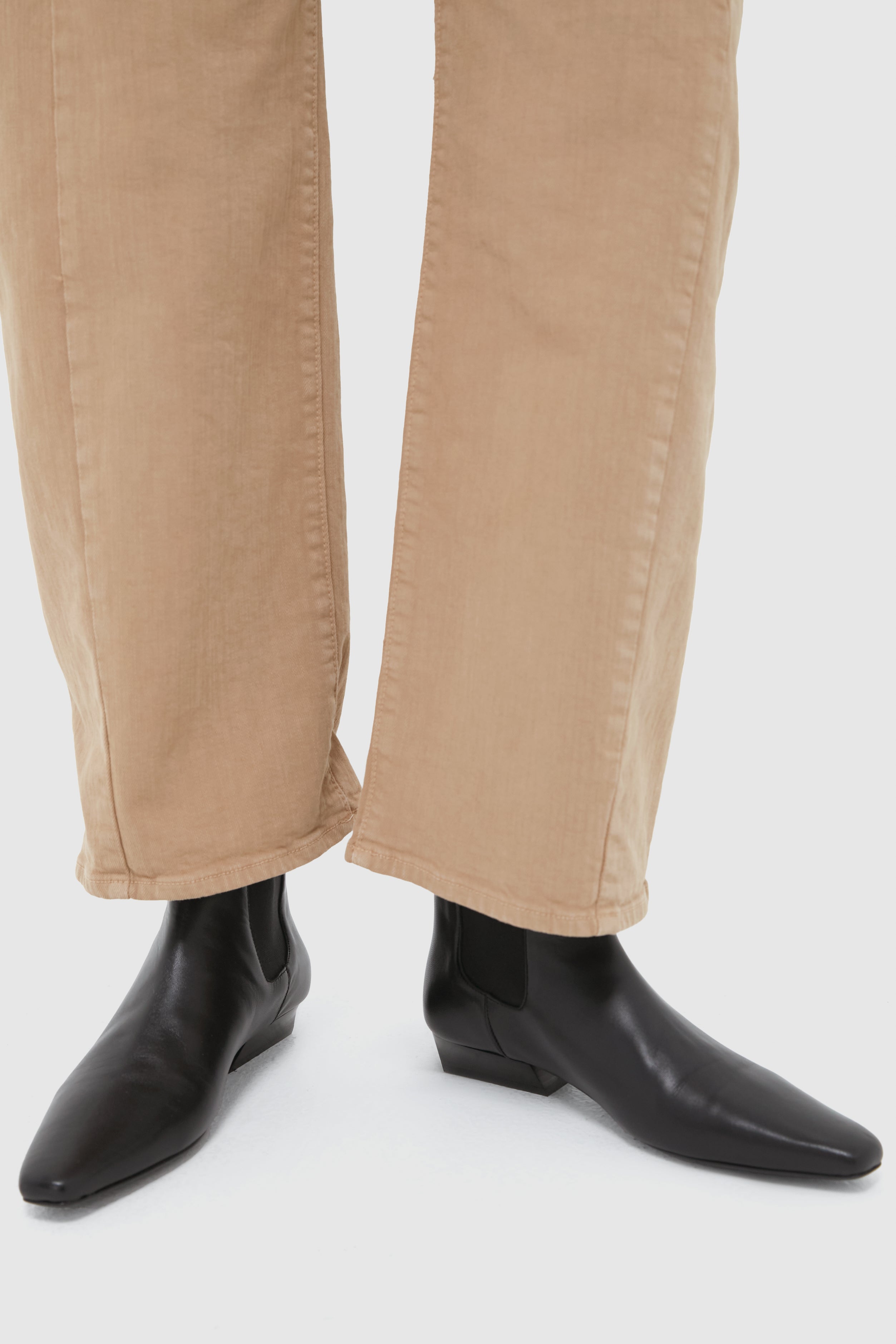 Black Wally Chelsea Boot in smooth leather, featuring a classic pointed toe and low block heel, styled with cropped trousers for an effortless, high-end look.