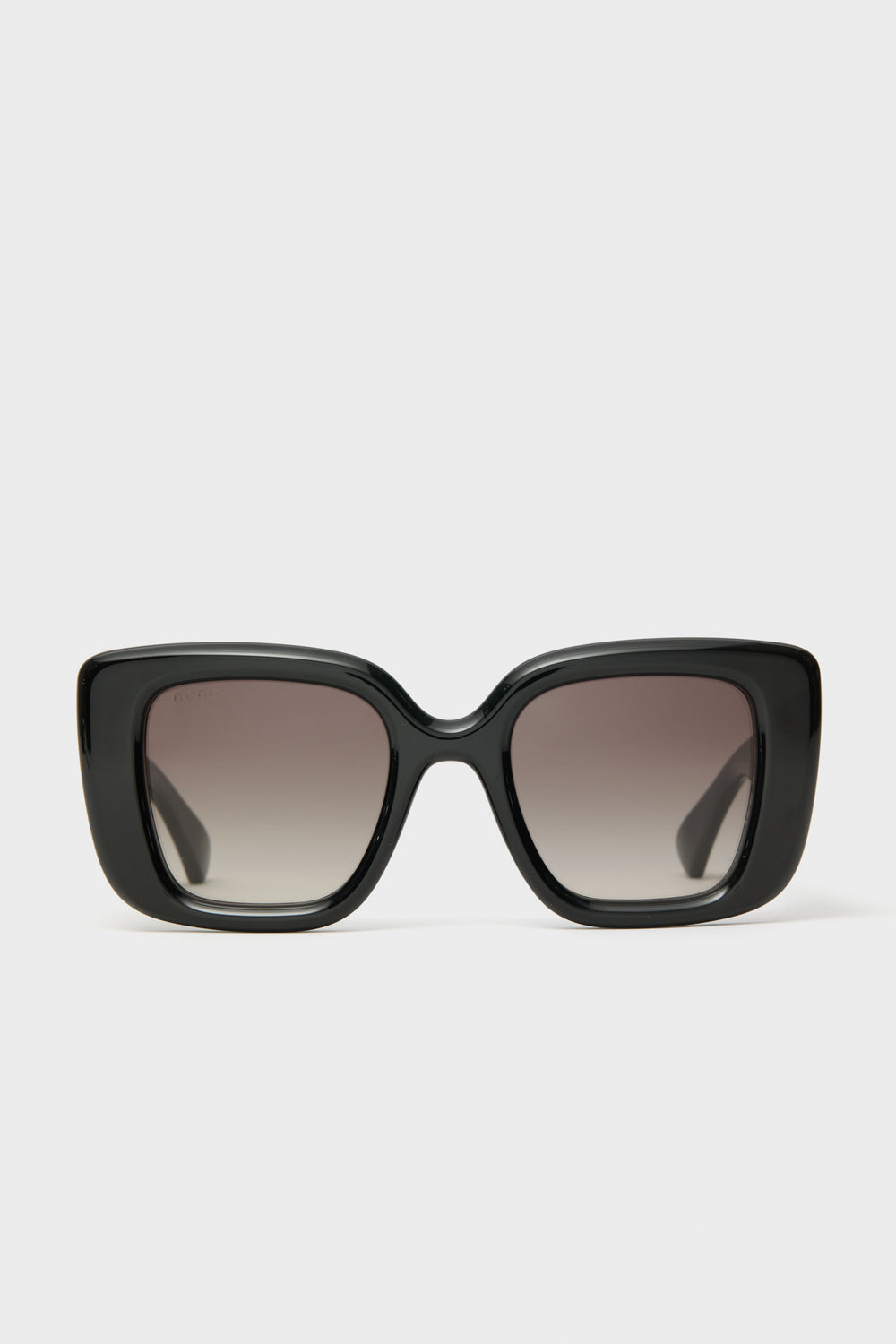 Front view of oversized black square sunglasses by Gucci with dark gradient lenses, showcasing luxury eyewear in a bold, statement-making style.