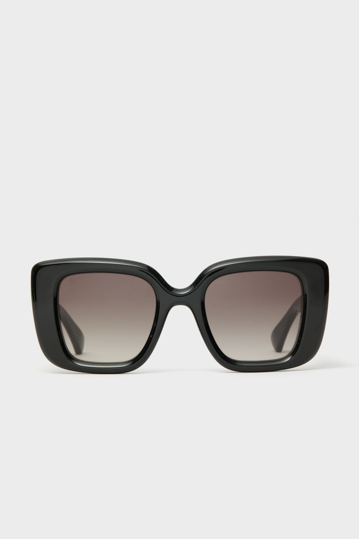 Front view of oversized black square sunglasses by Gucci with dark gradient lenses, showcasing luxury eyewear in a bold, statement-making style.