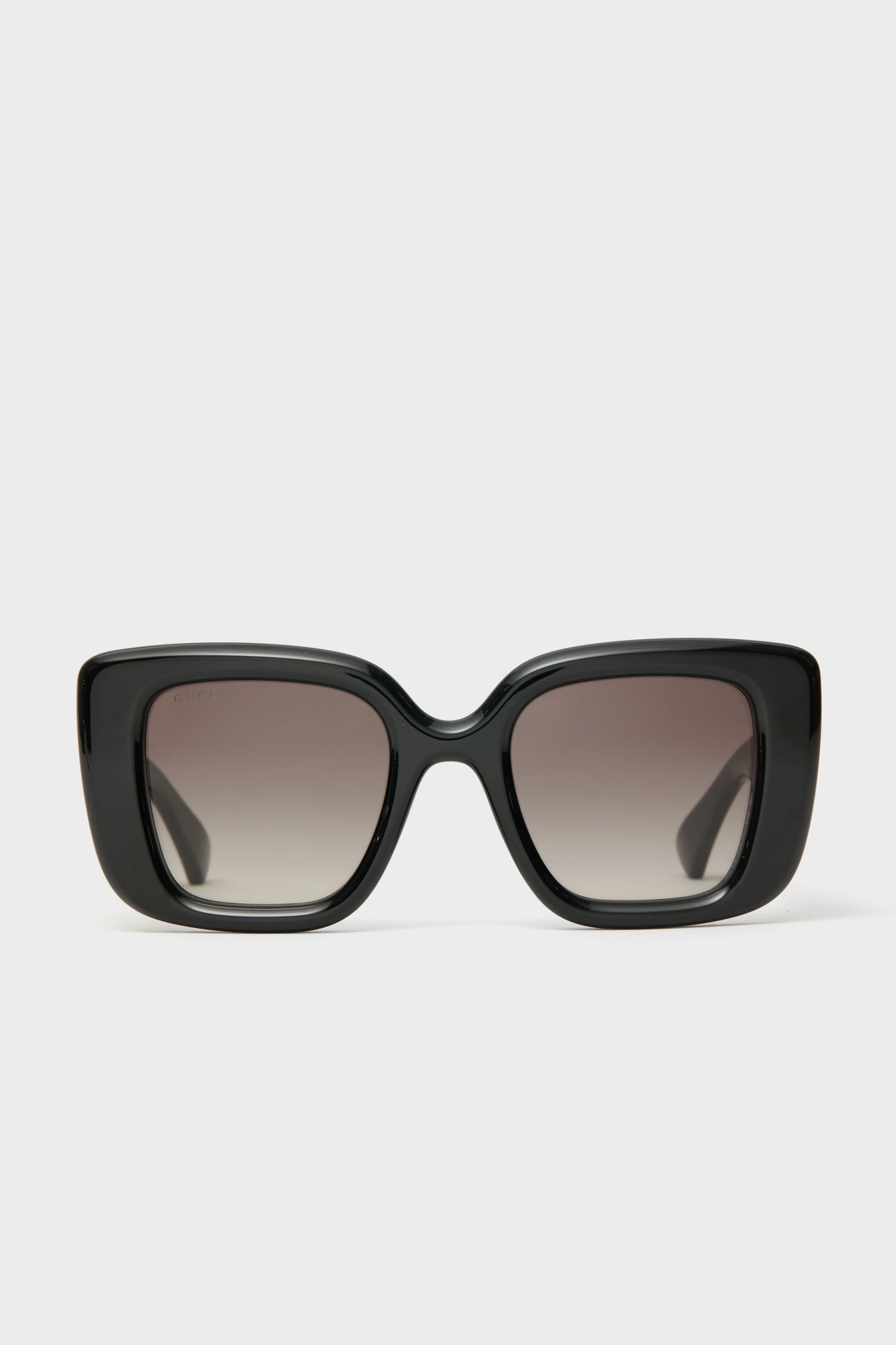 Front view of oversized black square sunglasses by Gucci with dark gradient lenses, showcasing luxury eyewear in a bold, statement-making style.