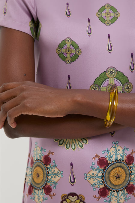 Close-up of crossed forearms wearing a lilac top, featuring the Apple Ridge Cuff—a classic, effortless, fun bangle in marbled pink resin, embodying high-end style.