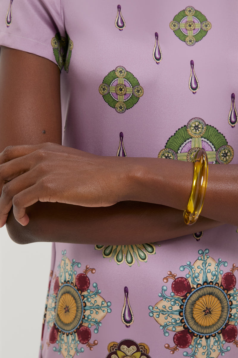 Close-up of crossed forearms wearing a lilac top, featuring the Apple Ridge Cuff—a classic, effortless, fun bangle in marbled pink resin, embodying high-end style.