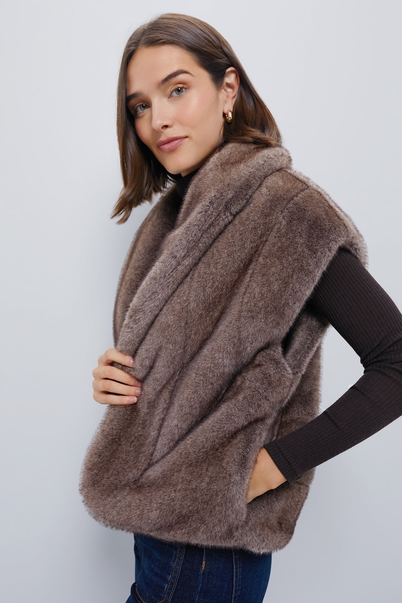 Woman models the Oversized Aspen Faux Fur Vest, showcasing its classic, effortless style and fun, high-end look, ideal for layering over a dark top.