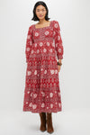 A woman wears a long red floral Lucia Dress by Pink City Prints, featuring long sleeves, 100% cotton fabric, and hand screen-printed details, paired with brown boots.